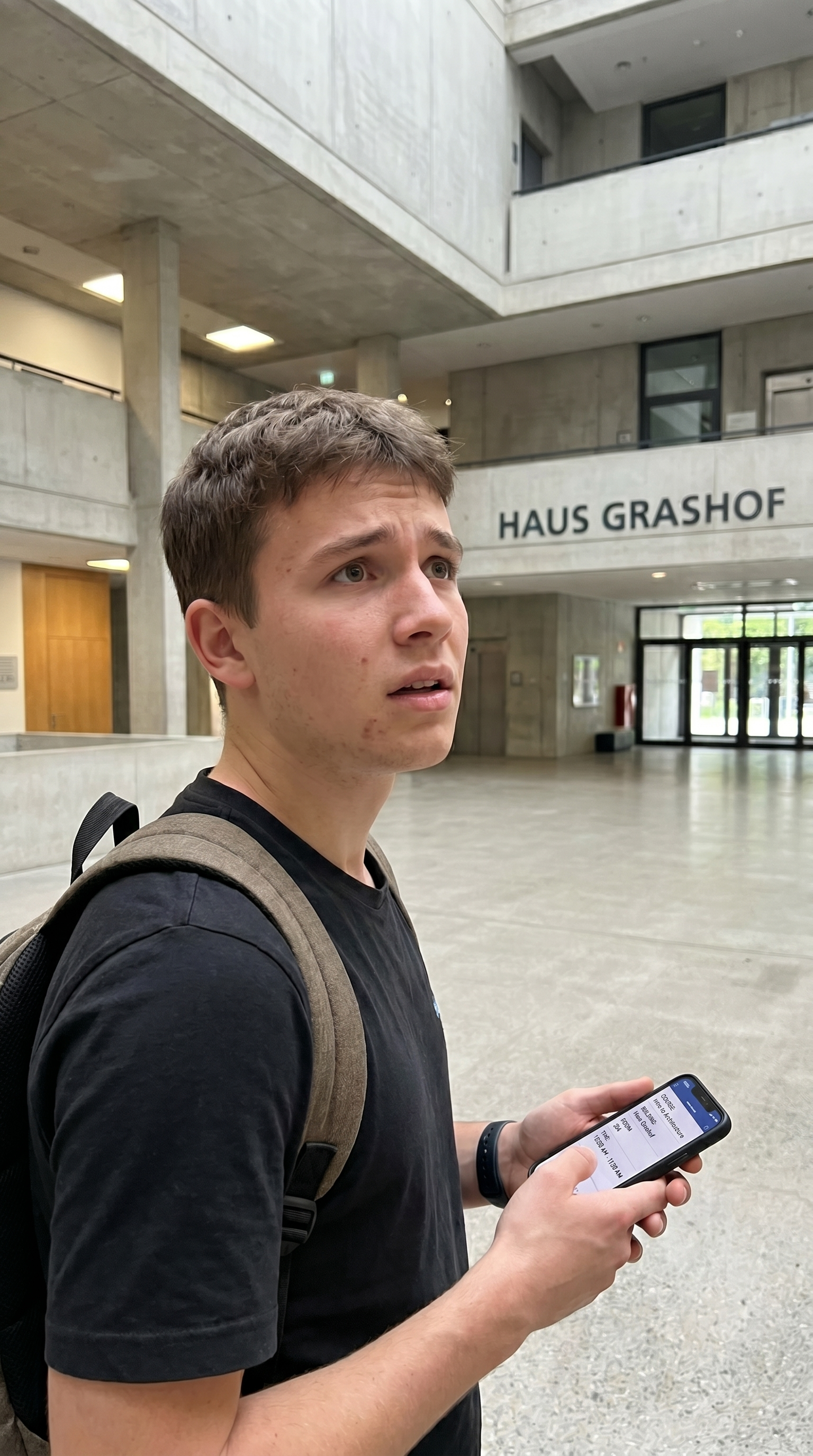 Jakob steht mit Smartphone im Haus Grashof und sucht nach Orientierung.